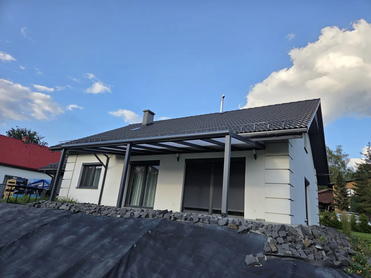 Hliníková pergola v antracitové barvě se střechou z polykarbonátu u přízemního domu