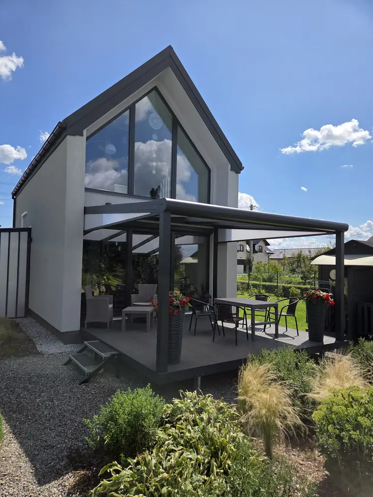 Hliníková pergola u moderního domu s prosklením ve štítu